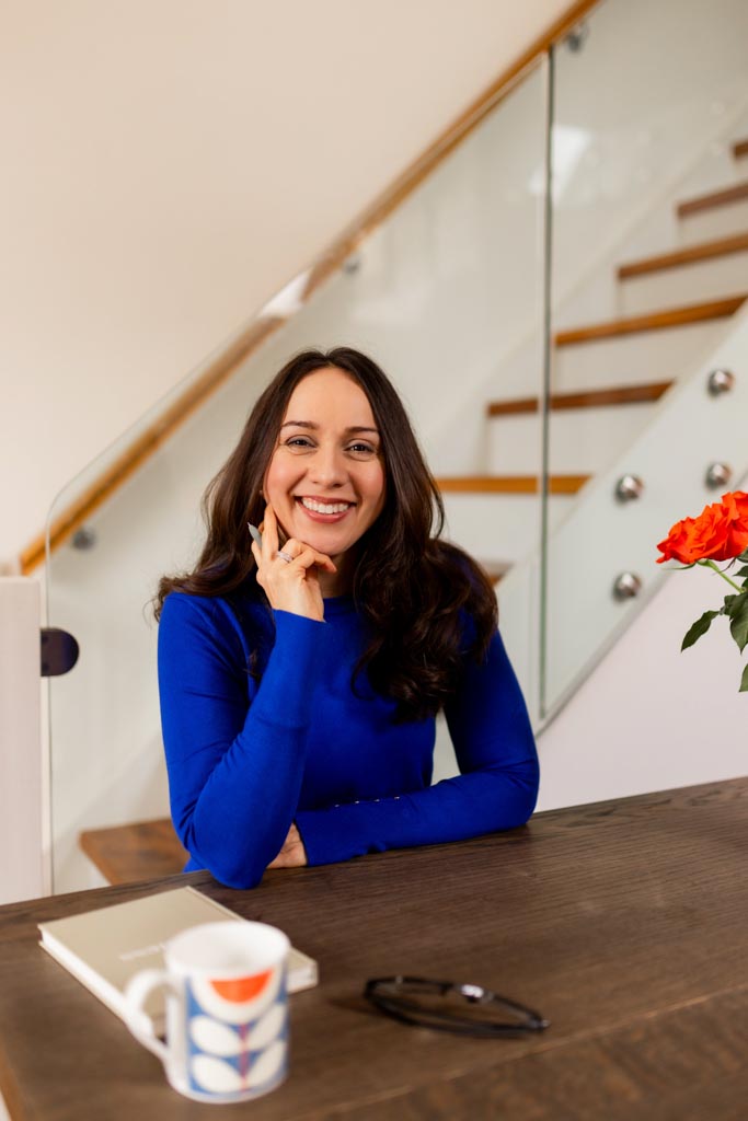 Angeli Degardin wearing a blue top smiling in front of stair case